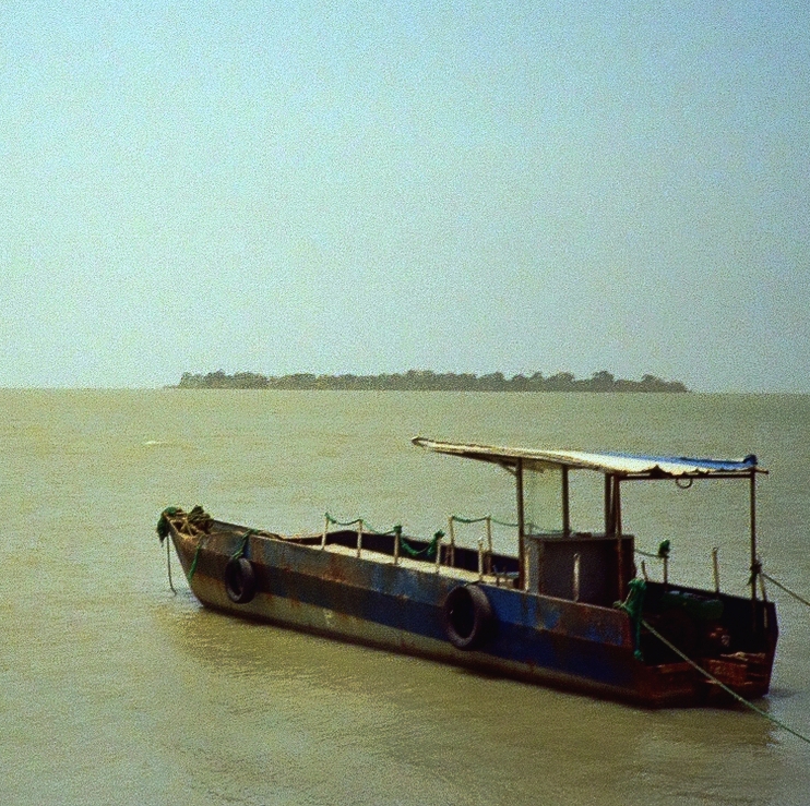 rust and paint covered fishing boat in the green waters of the Bissau docks