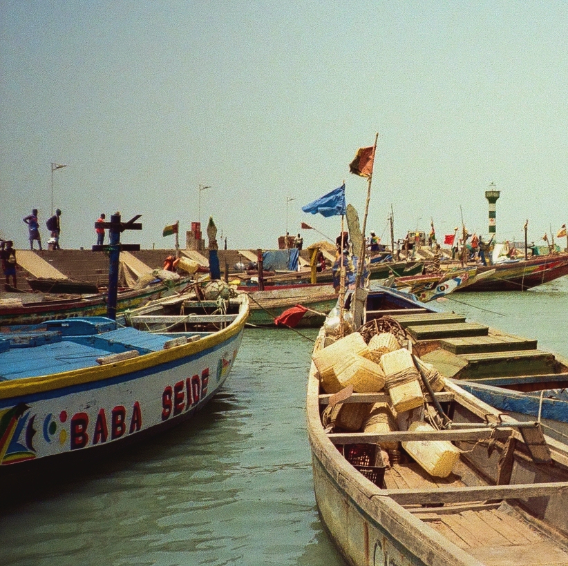 colorful fishing boats in the Bissau docks with a crowed on the pier in the background