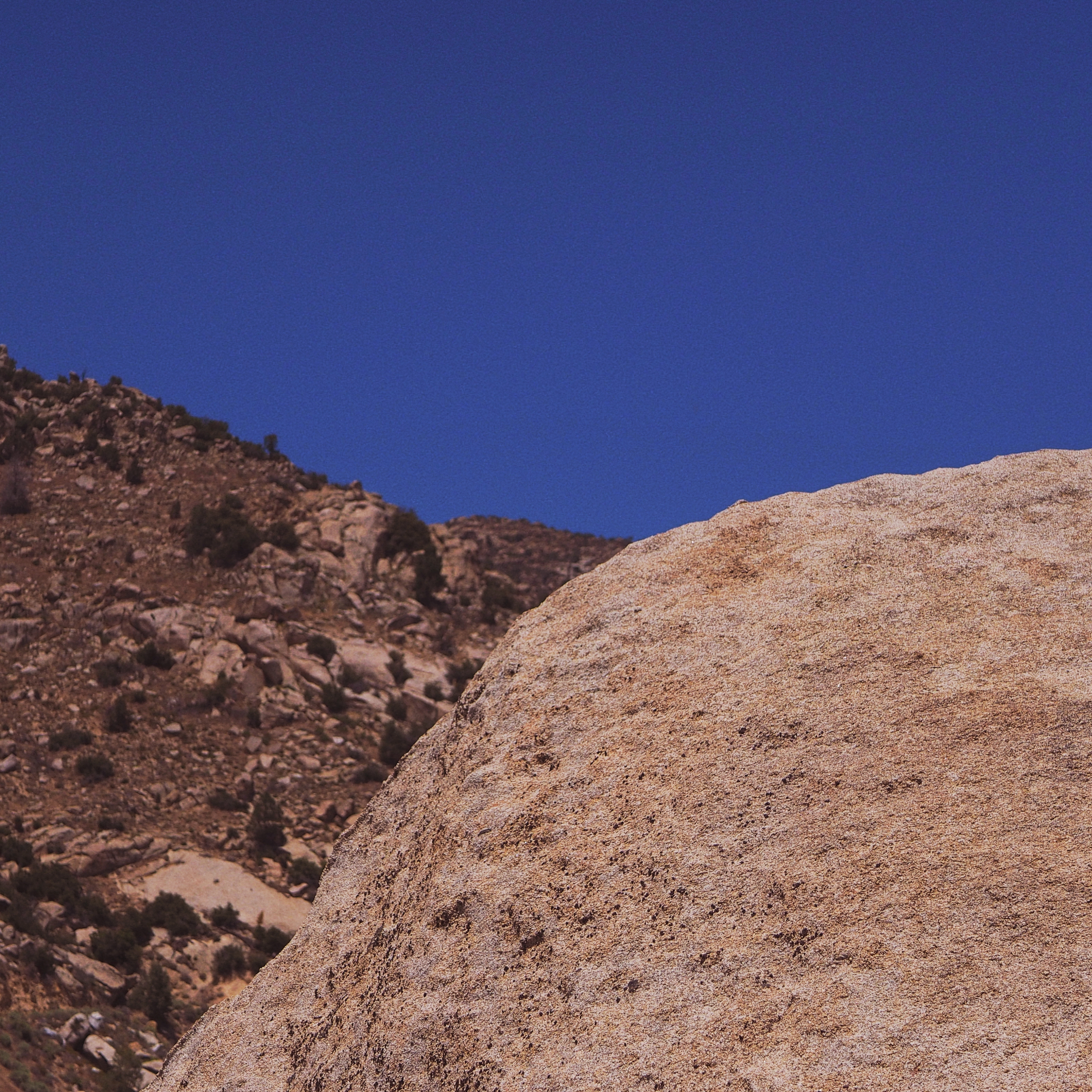 two large boulders in the desert with clear blue sky above