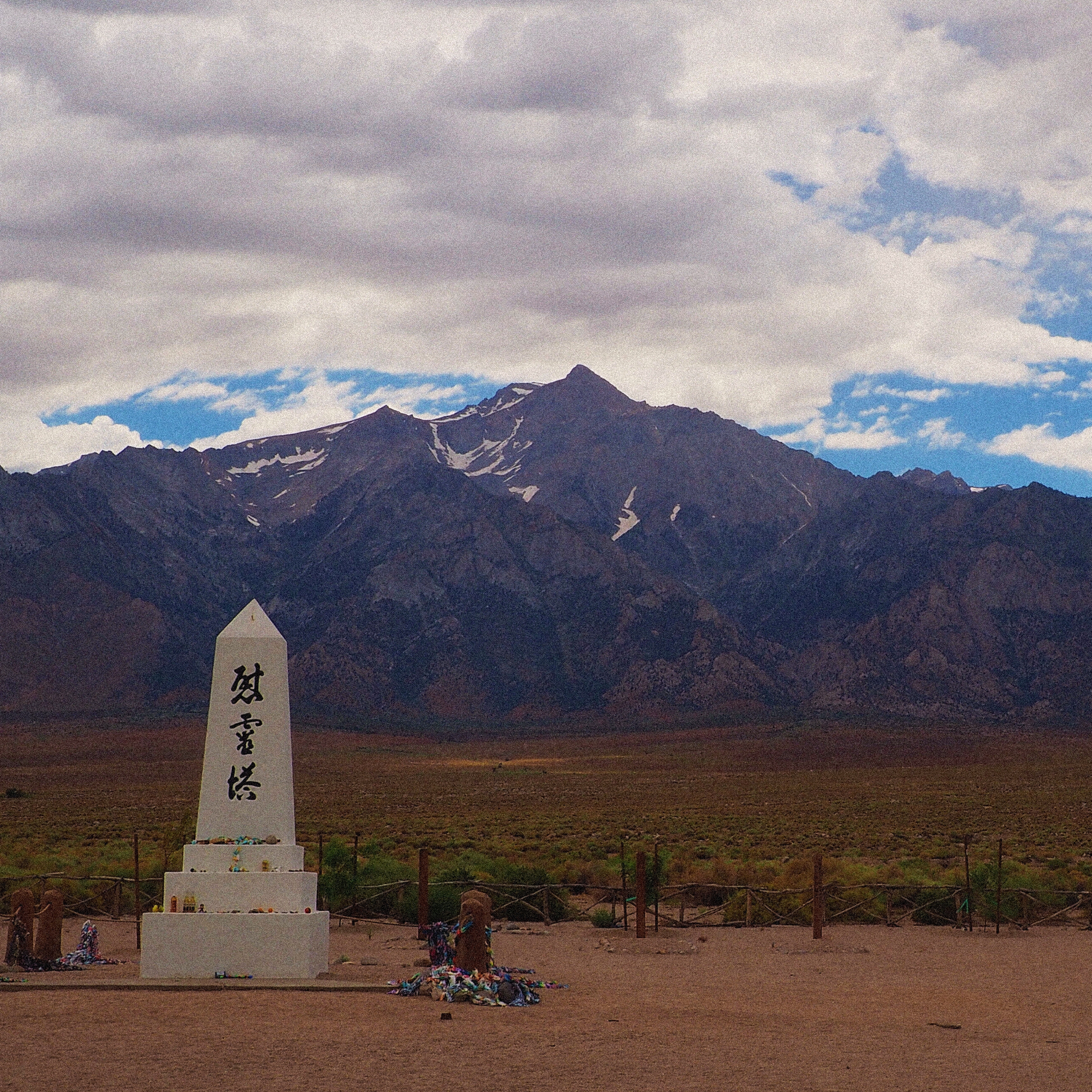 marble memorial at the manzanar internment camp with snowy mountains and clouds in the background